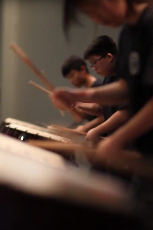 A row of youth drumming on traditional Korean drums.